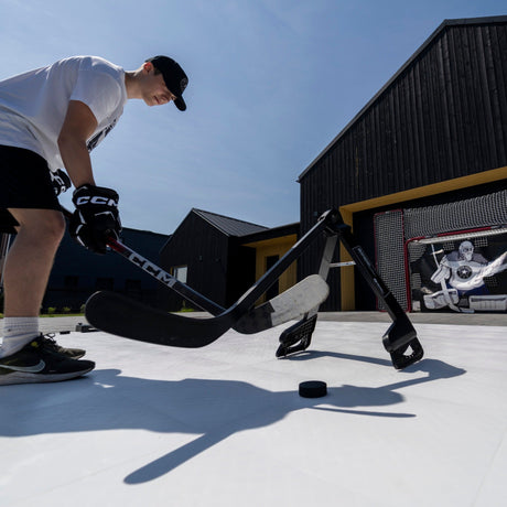 Hockey player working the puck past a Pro Defender trainer on an outdoor rink