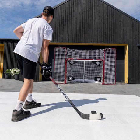 Hockey player practicing shooting drills on training tiles toward a net with corner targets