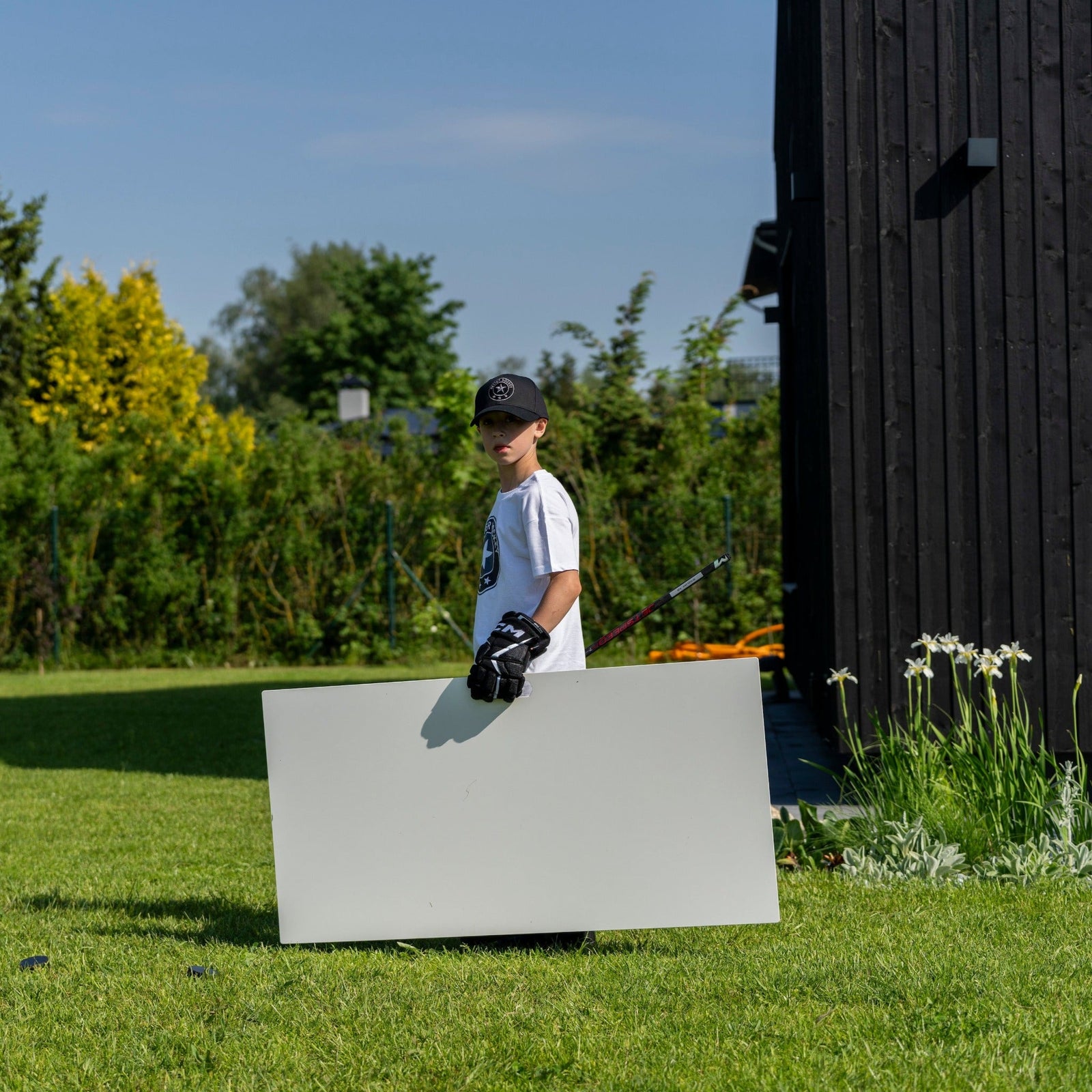 Young hockey player in a backyard holding an Extreme shooting pad for in-tight scoring practice