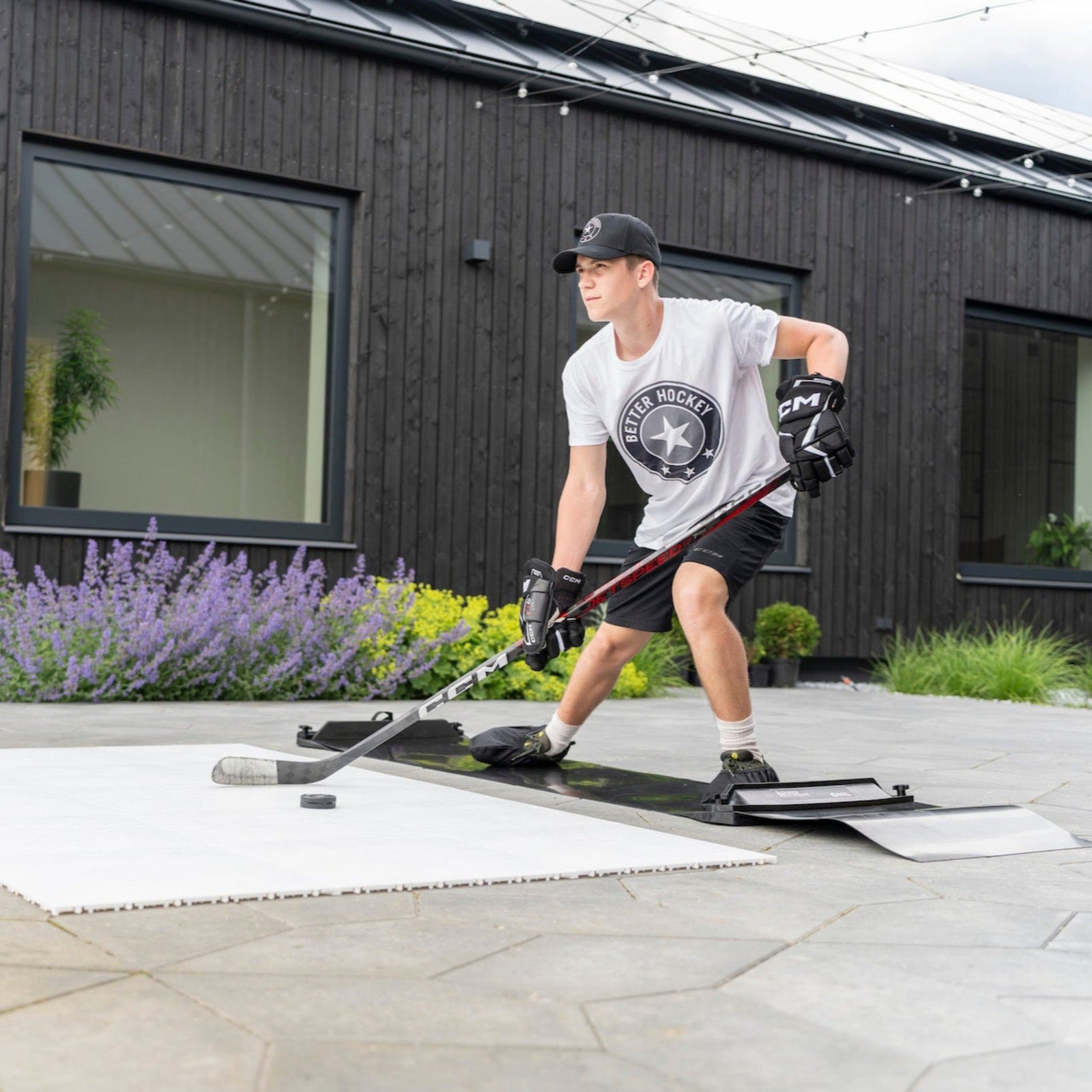 Hockey player in full extension on a slide board training in a backyard patio, Better Hockey gear