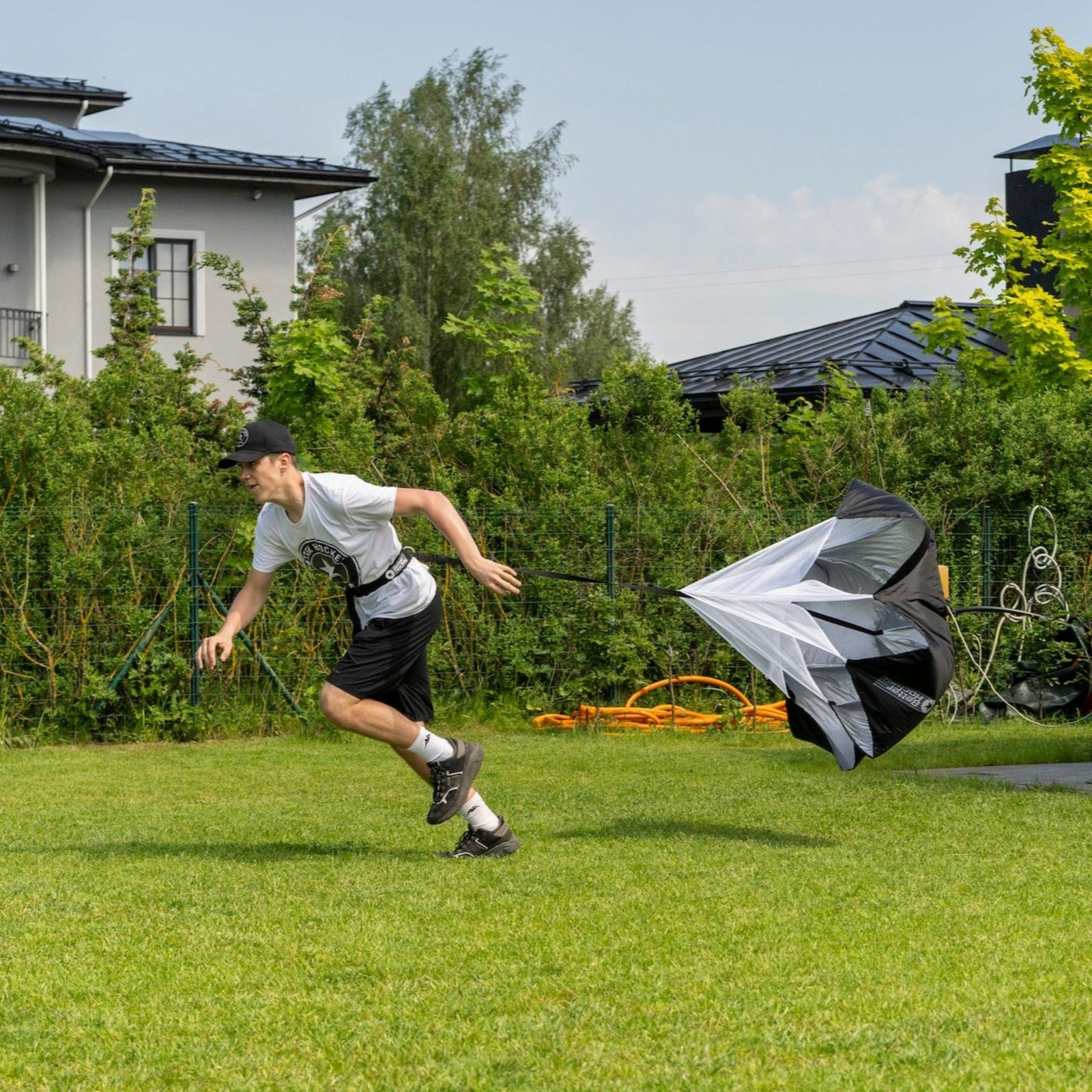 Hockey player running outdoors pulling a speed chute during pre-season conditioning training