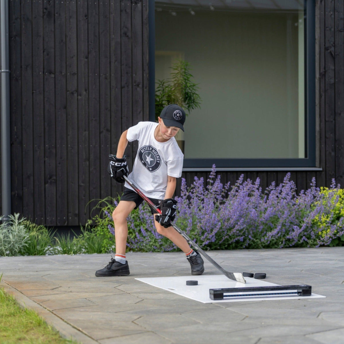 Young hockey player practising passing and stickhandling outdoors with a rebounder on a patio