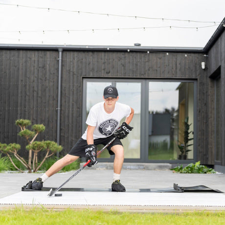 Young player training the skating push and glide on a slide board in a backyard
