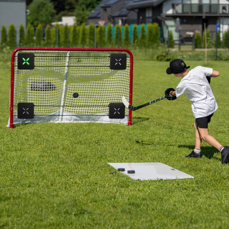 Young hockey player training shooting accuracy in the backyard with corner targets in the net
