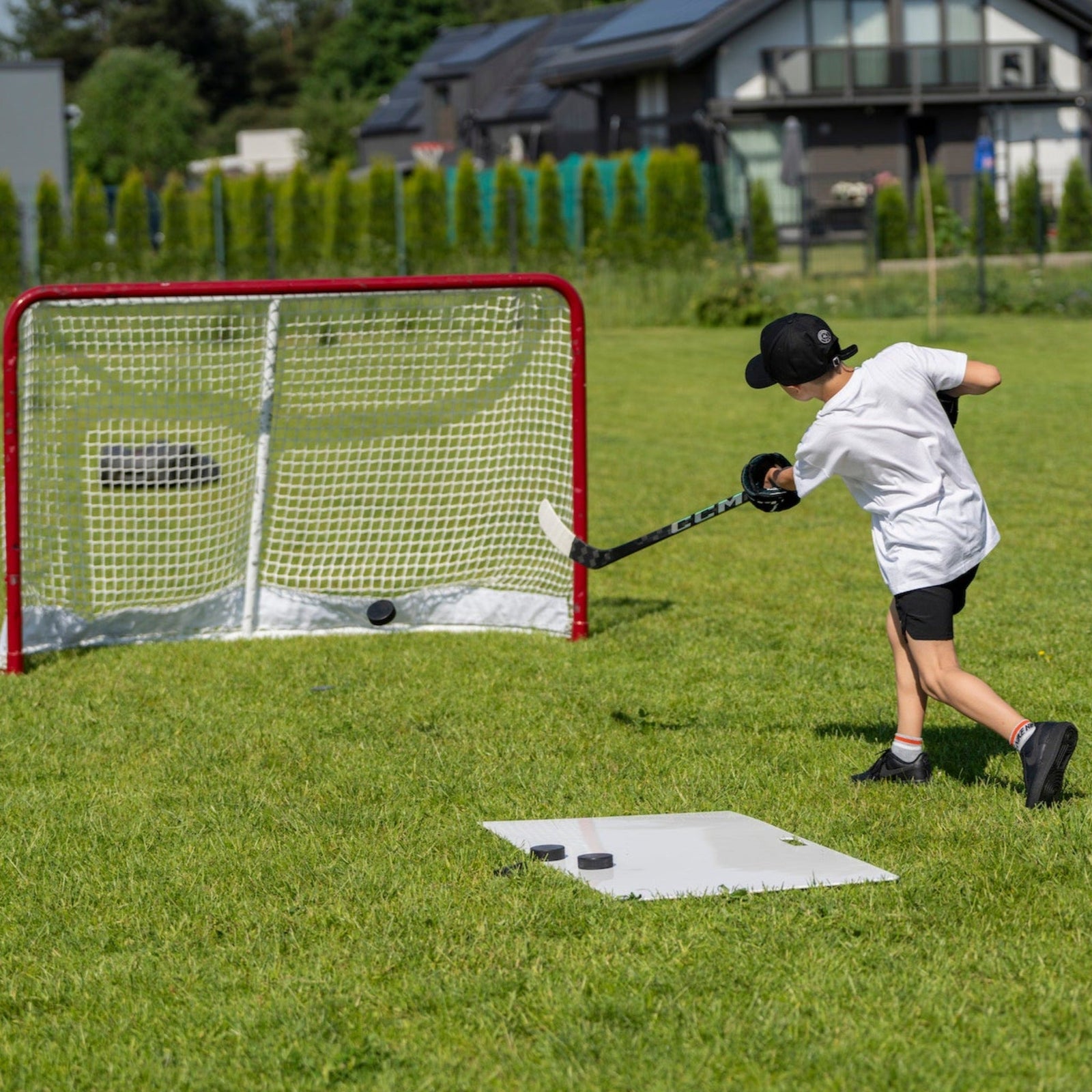 Young hockey player shooting on goal in the backyard from a shooting pad during tryout preparation
