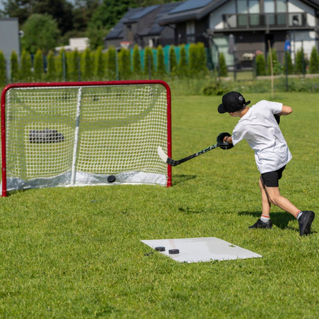 Young hockey player shooting on goal in the backyard from a shooting pad during tryout preparation