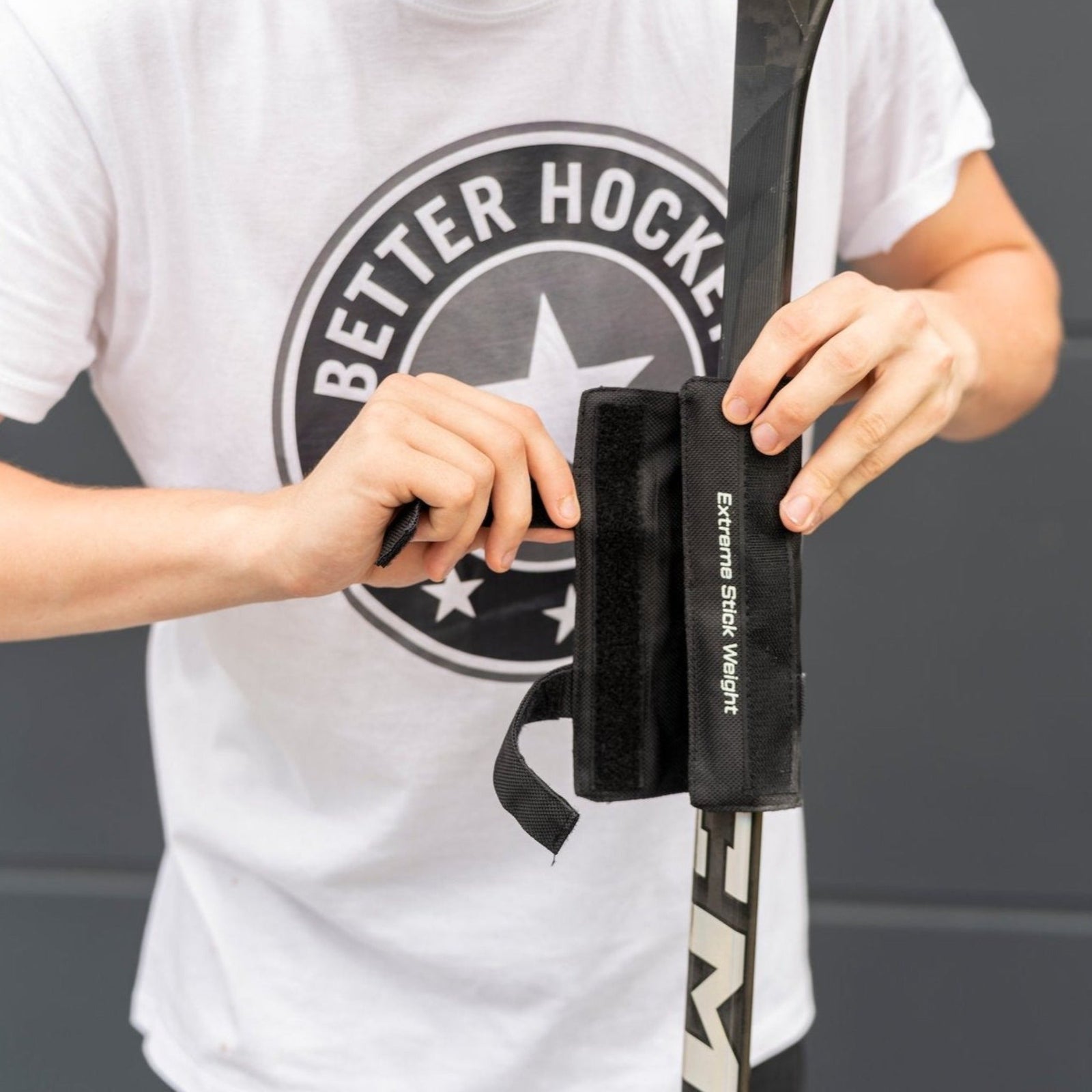 Young player attaching a Better Hockey stick weight to the shaft of a hockey stick