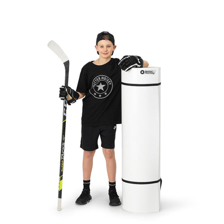 Young hockey player standing next to a rolled-up Extreme Hockey shooting pad ready for transport