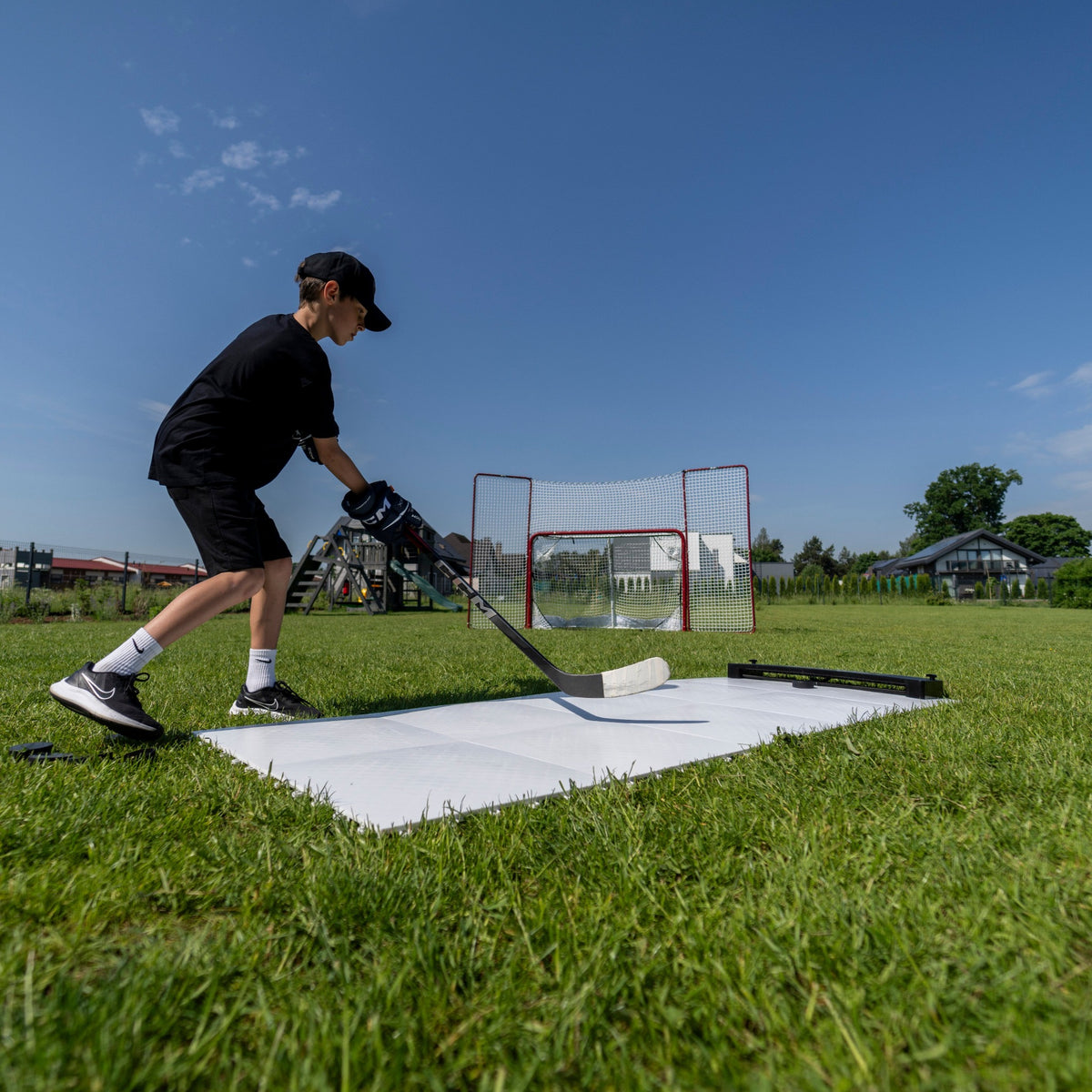 Player stickhandling on synthetic ice hockey tiles on the lawn